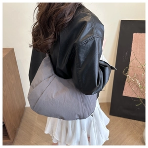 Sac bandoulière en nylon gris matelassé porté par un mannequin pour un look décontracté