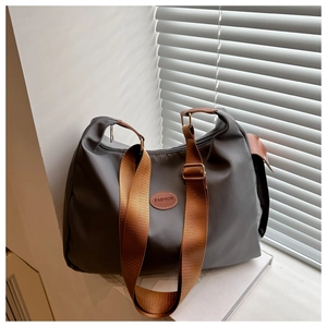 Detailed shot of grey waterproof nylon tote with brown strap and leather label detail