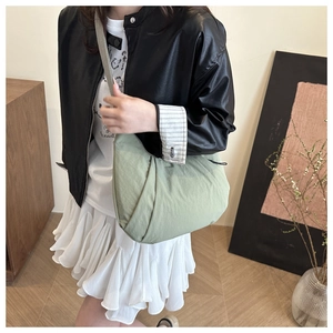 Détail du sac demi-lune vert clair avec design plissé et bandoulière large grise