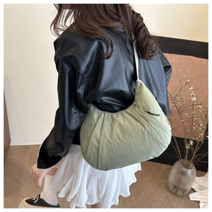 Vue latérale du sac croissant vert olive avec texture plissée sur mannequin
