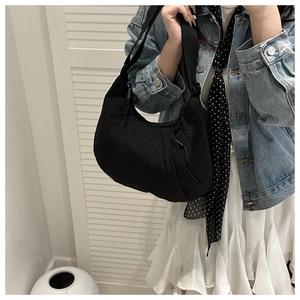 Gros plan d'un sac bandoulière en nylon noir plissé porté par un mannequin en style décontracté