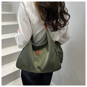 Detail of army green nylon tote bag with leather logo and brown wide woven strap