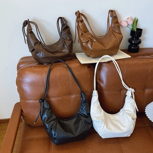 Minimalist pleated crescent bag in four colors displayed on a sofa for casual styling