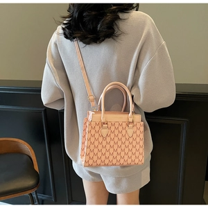 Sac bandoulière rose avec motif M et logo doré porté à l'épaule par un mannequin