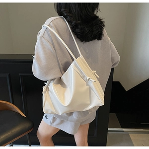 Dettaglio borsa a secchiello bianca lucida con tracolla annodata in stile minimalista