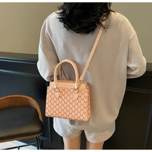 Gros plan du sac à bandoulière rose avec motif monogramme et boucle en métal