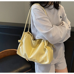 Dettaglio della borsa tote in pelle morbida giallo chiaro con nodi laterali decorativi