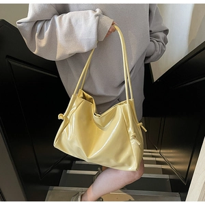 Dettaglio della borsa tote in pelle verniciata gialla con nodo laterale decorativo
