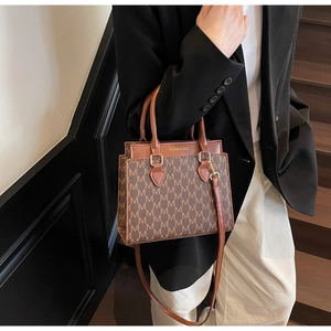 Détail d'un sac cabas marron à carreaux avec inscription FASHION & BAGS et motif M