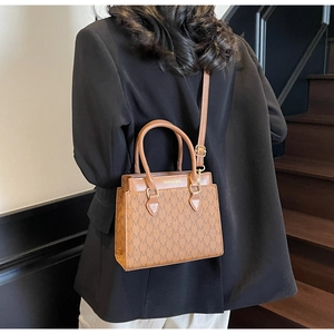 Sac fourre-tout marron à monogramme avec bandoulière réglable porté par un mannequin