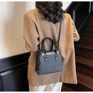 Detail of grey monogram tote bag with gold lettering shown on model in a suit