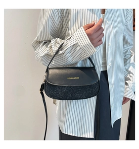 Detail of black leather and glitter patchwork handbag with gold lettering and strap