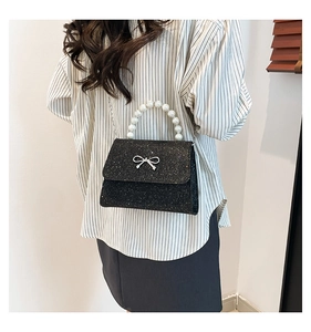 Close-up of black sequined handbag with pearl handle and silver metal bow detail