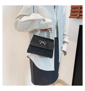 Detail of black sequined handbag featuring a luxury pearl handle and silver bow buckle