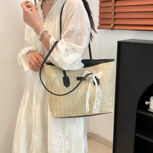 Summer woven straw tote bag with black leather handles and white lace bow detail