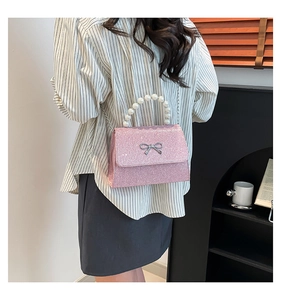 Schicke rosa Glitzertasche mit Perlengriff und silberner Schleife an einem Model