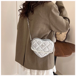 Detailed view of silver heart-shaped crossbody bag with quilted pattern and pearl chain