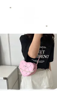 Pink heart-shaped crossbody bag with quilted texture, pearl chain, and bow detail on model
