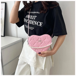 Detailed view of pink heart-shaped bag featuring quilted pattern and pearl chain accent