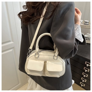 Creamy white glossy handbag worn by a model in grey suit showing the stylish side view