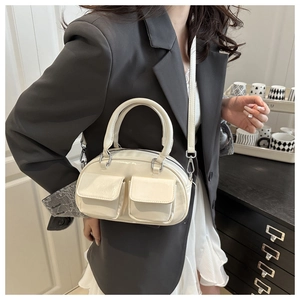 Chic cream glossy underarm bag with double front pockets styled on a model in a gray blazer