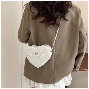 Rear view of model wearing white heart-shaped quilted crossbody bag with pearl chain