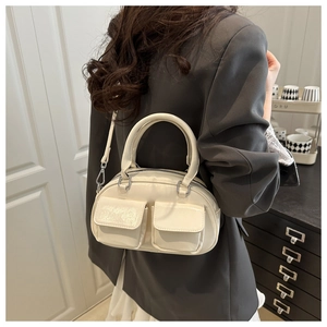 Close-up of stylish cream white Boston shoulder bag with dual front pockets on a model