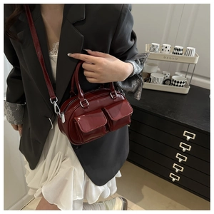 Detail of burgundy patent leather tote bag with silver metal hardware and double front pockets