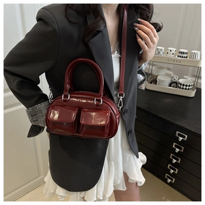 Detail of burgundy patent leather handbag featuring dual front pockets and silver hardware
