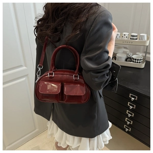Detail of burgundy glossy crossbody bag with dual flap pockets and silver metal hardware