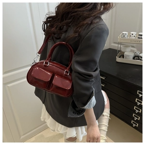 Detail of burgundy patent leather Boston bag with dual pockets and silver hardware