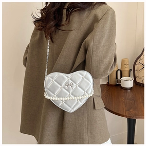 Detail of silver heart-shaped quilted bag with pearl trim and elegant metal chain strap