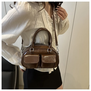 Detail view of glossy dark brown tote bag with twin front pockets and silver hardware