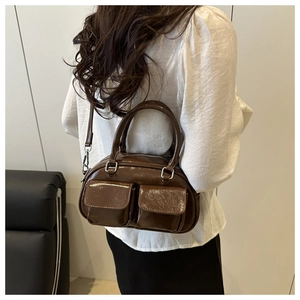 Detail of dark brown polished leather crossbody bag with double front flap pockets