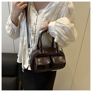 Detail of dark brown glossy leather tote bag showing pocket texture and silver hardware