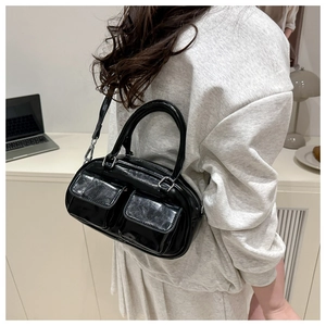 Detail of black patent leather underarm bag with double front pockets and silver buckles