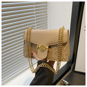 Détail de la texture en cuir gaufré floral et chaîne dorée sur un petit sac bandoulière