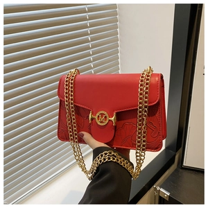Détail du sac bandoulière en cuir rouge avec motif feuille gaufré et boucle M dorée