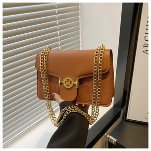 Détail du sac en cuir marron avec motifs floraux gaufrés et boucle dorée en M