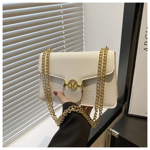 Détail d'un sac beige avec gaufrage floral et fermoir métallique doré arborant le logo M