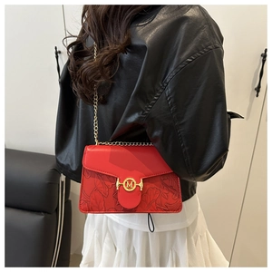 Gros plan du sac bandoulière rouge avec relief floral et chaîne dorée à boucle M