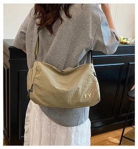 Vue détaillée du sac bandoulière en nylon kaki porté par un mannequin dans un salon