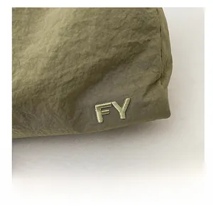 Détail de la texture en nylon vert armée avec broderie raffinée des lettres FY