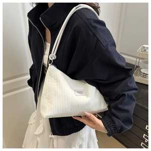 Detail of white pleated shoulder bag featuring textured fabric and rope strap on model