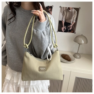 Detail of pleated texture and leather brand tag on large striped tote shoulder bag