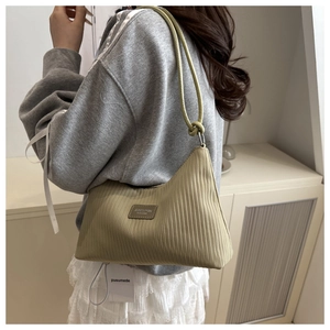 Detailed view of olive green pleated tote bag featuring a brand label and knotted strap