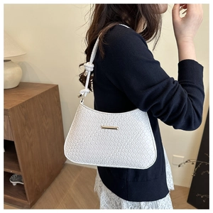 Detail of white woven leather shoulder bag with gold metal bar and knotted strap