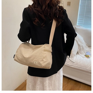 Vue détaillée du sac bandoulière en nylon beige avec broderie FY et étiquette fashion