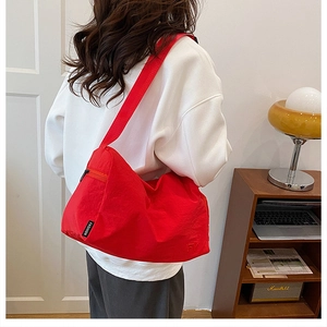 Détail du sac croissant en nylon rouge avec bandoulière large et étiquette de mode