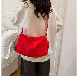 Détail du sac cabas en nylon rouge avec broderie FY et bandoulière réglable